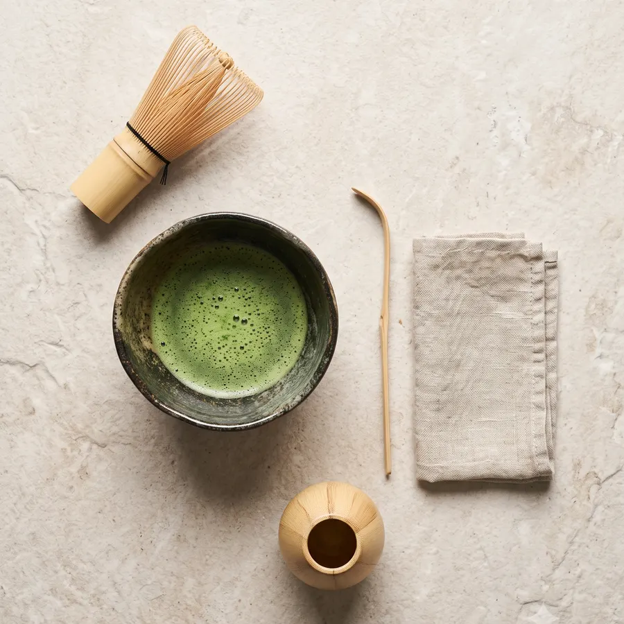 Bowl, whisk, scoop and linen laid out on stone